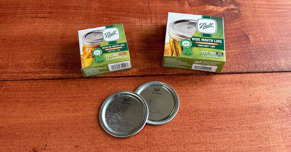 Two boxes of Ball mason jar lids with two separate lids.