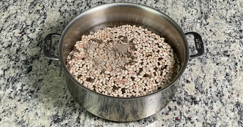 Dry Pinto beans in a stainless steal pot covered in water. Beans are being rehydrated before Pressure Canning.