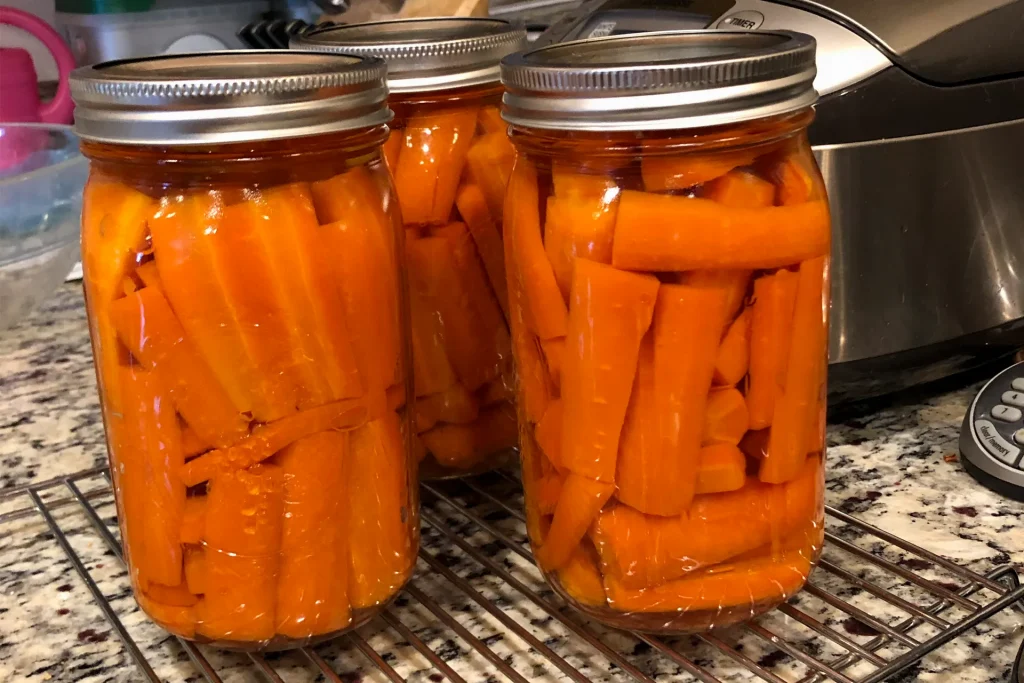 Three quart size mason jars of canned carrots. They were canned using a pressure canner.