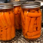 Three quart size mason jars of canned carrots. They were canned using a pressure canner.