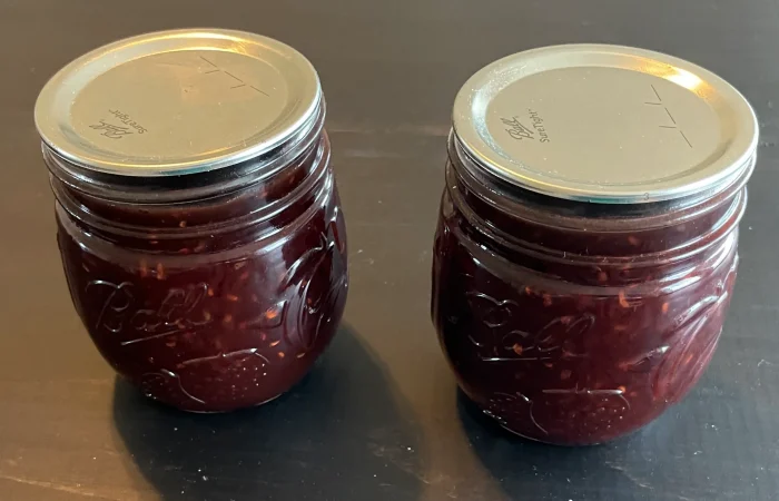 Two mason jars of Chocolate Raspberry Sauce that has been Water Bath Canned.