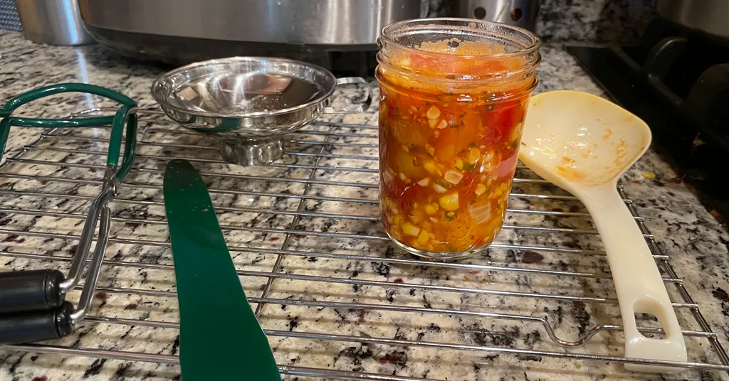 Half pint mason jar full of corn and cherry tomato salsa from Ball Canning's recipe.