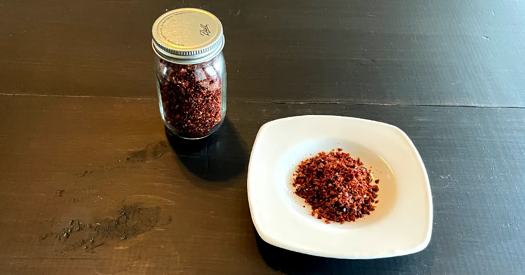 Paprika powder in a pile on a white dish. Paprika powder in a glass spice jar.
