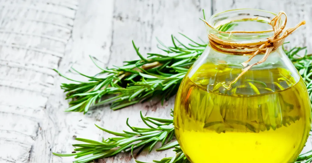 Sprigs of Rosemary next to a jar of oil that will be used as an rosemary oil infusion.