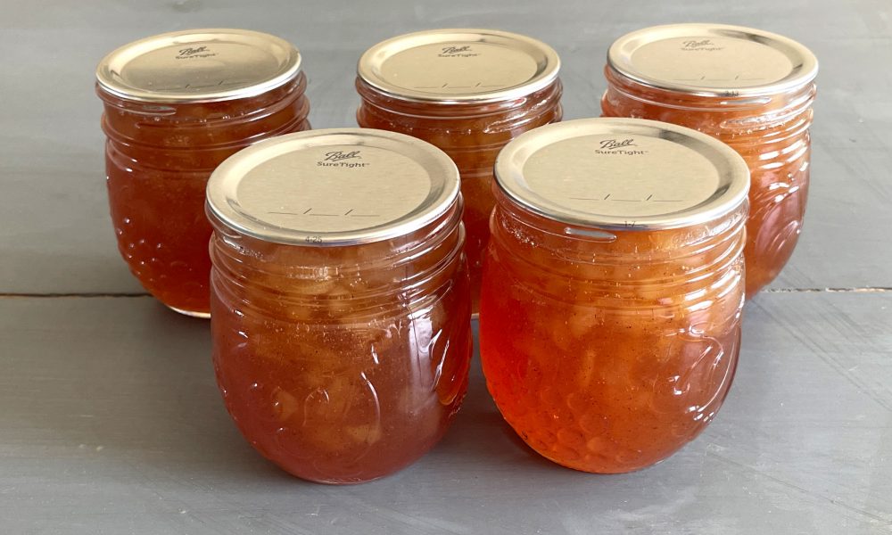 Image of five mason jars of pear jam that have been water bath canned.