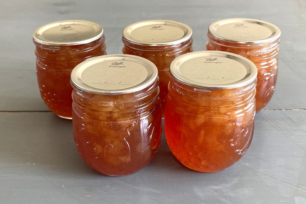 Image of five mason jars of pear jam that have been water bath canned.