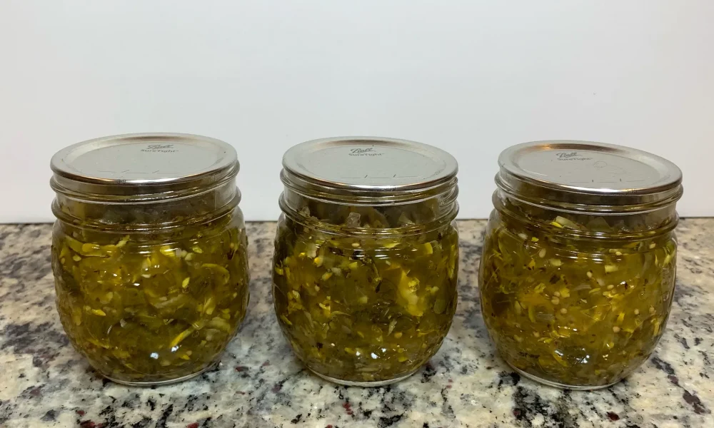 Three mason jars of zucchini relish that has been water bath canned