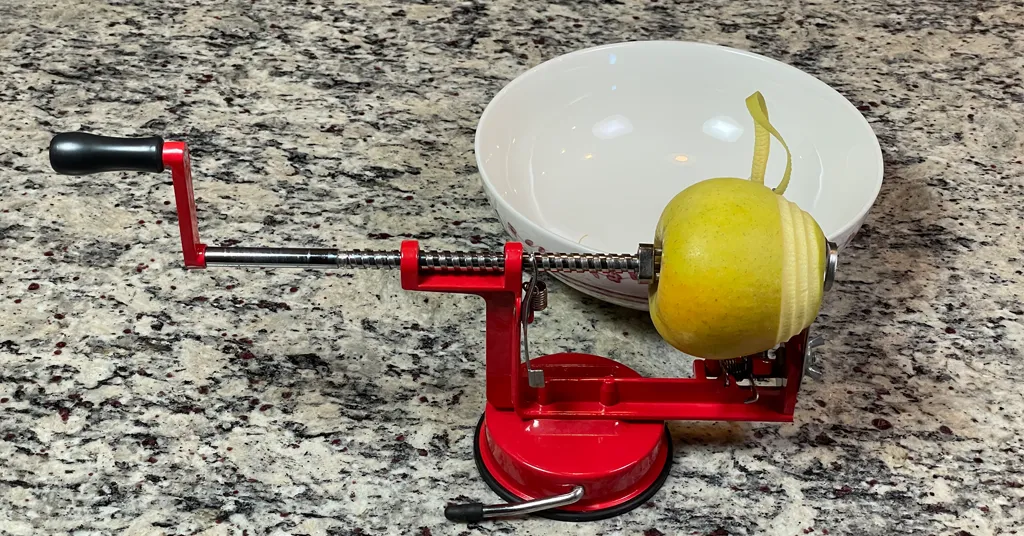 Apple being peeled using an apple corer, peeler, slicer.