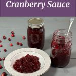 Pinterest Pin for How To Water Bath Can Cranberry Sauce. Two mason jars of homemade cranberry sauce. One is open and the cranberry sauce has been scooped into a bowl.