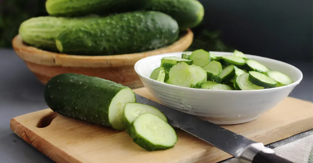 Cucumbers being sliced into slices. Cucumbers slices sitting in a white bowl.