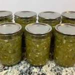Seven half pint mason jars of salsa verde sitting on a counter