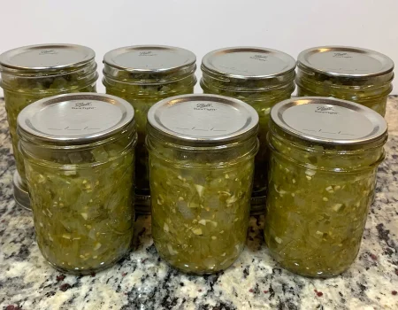 Seven half pint mason jars of salsa verde sitting on a counter