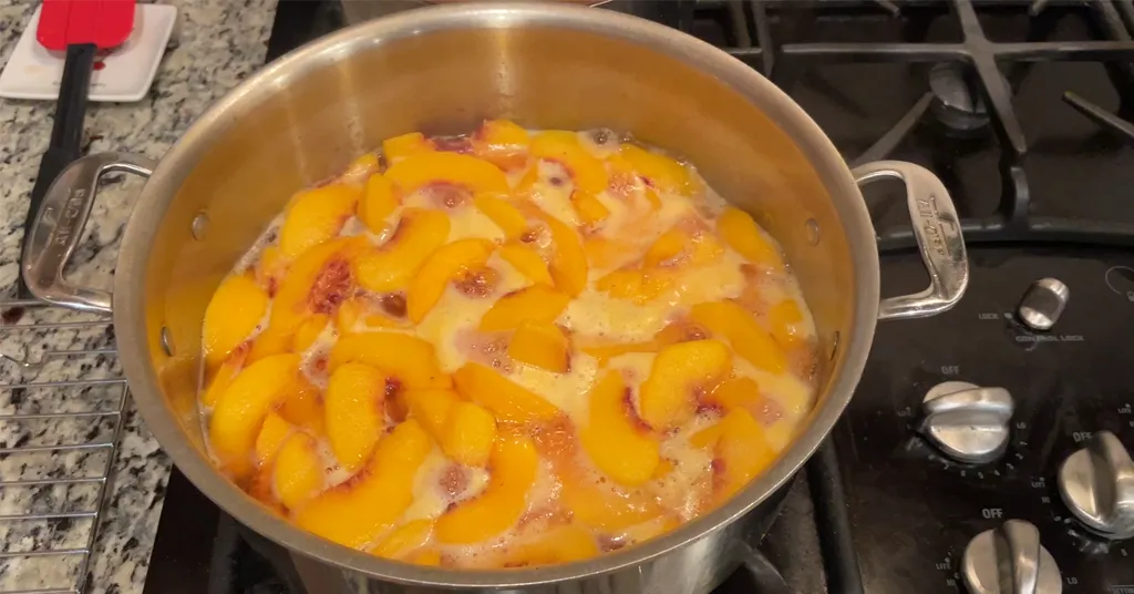 Peach slices soaking in light syrup before canning