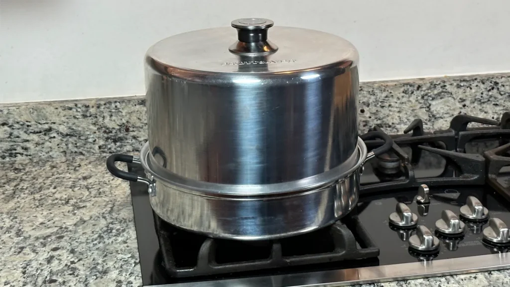A Fruitsaver atmospheric steam canner sitting on a stove.