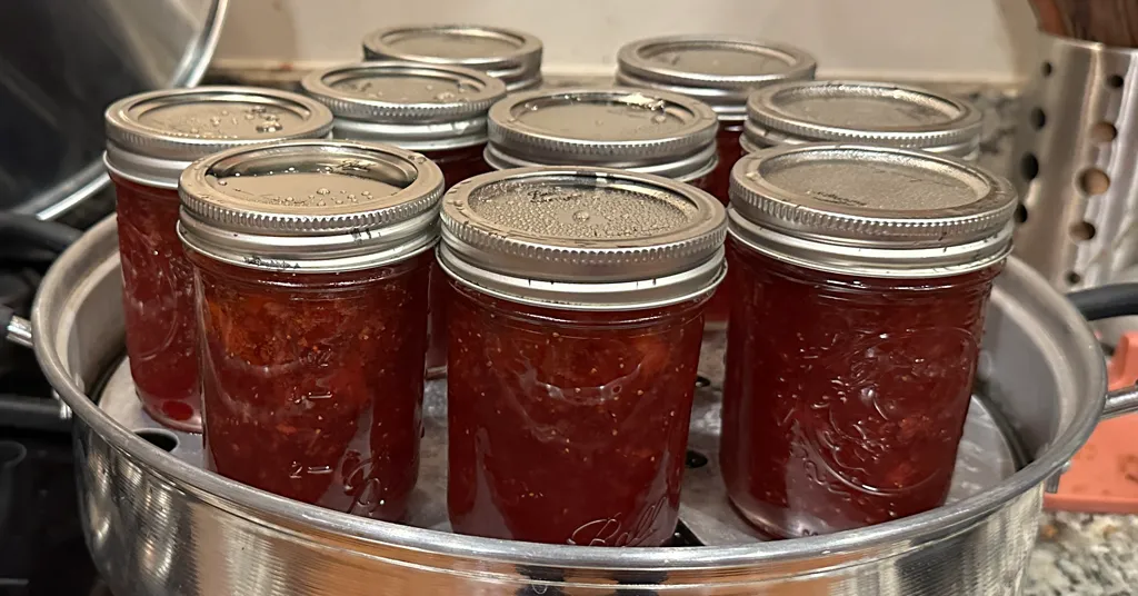 Nine half pint mason jars of strawberry jam that were processed in a steam canner.