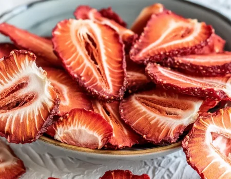 Dehydrated Strawberry slices in a bowl sitting on a white counter.