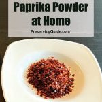 Pinterest Pin for How to Make Paprika Powder at Home. Image of dehydrated paprika powder sitting on a white plate on a dark surface.