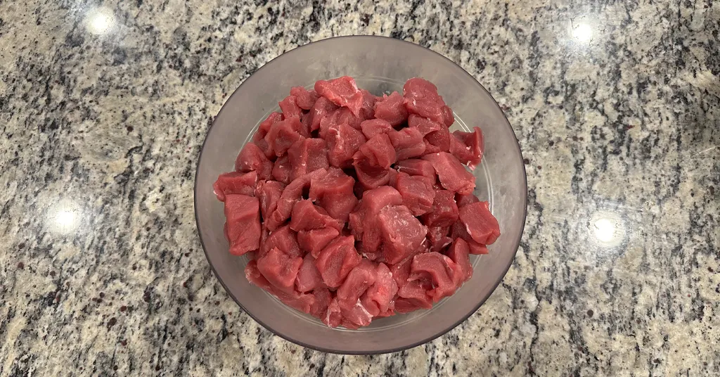 One inch pieces of pork tenderloin sitting in a glass bowl on a counter.