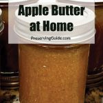 Image of several jars filled with apple butter, with the text "How To Can Apple Butter at Home" and "PreservingGuide.com" displayed prominently in the center. The jars are sealed and sitting on a kitchen countertop, indicating a homemade canning process.