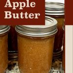 Image of sealed jars of apple butter on a kitchen countertop, with the text "Apple Butter" prominently displayed on a brown background. The design includes a beige border and the website "PreservingGuide.com" at the bottom, highlighting the apple butter and its source for preservation guidance.