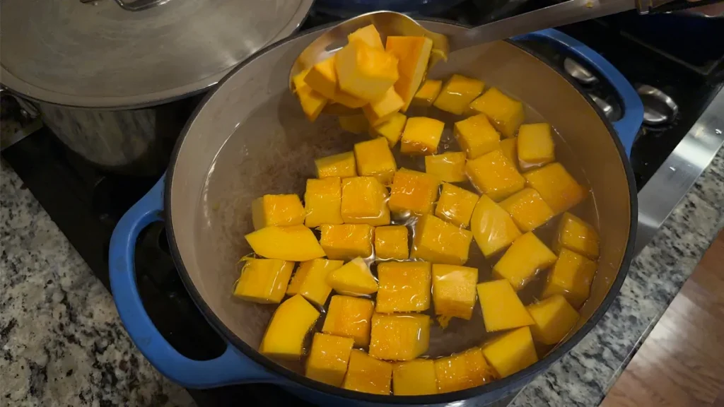 Pumpkin cubes being blanched in a pot of boiling water.