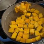 Pumpkin cubes being blanched in a pot of boiling water.