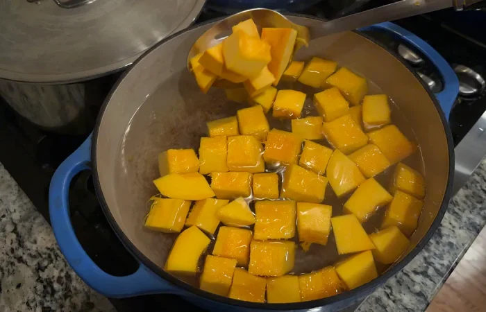 Pumpkin cubes being blanched in a pot of boiling water.