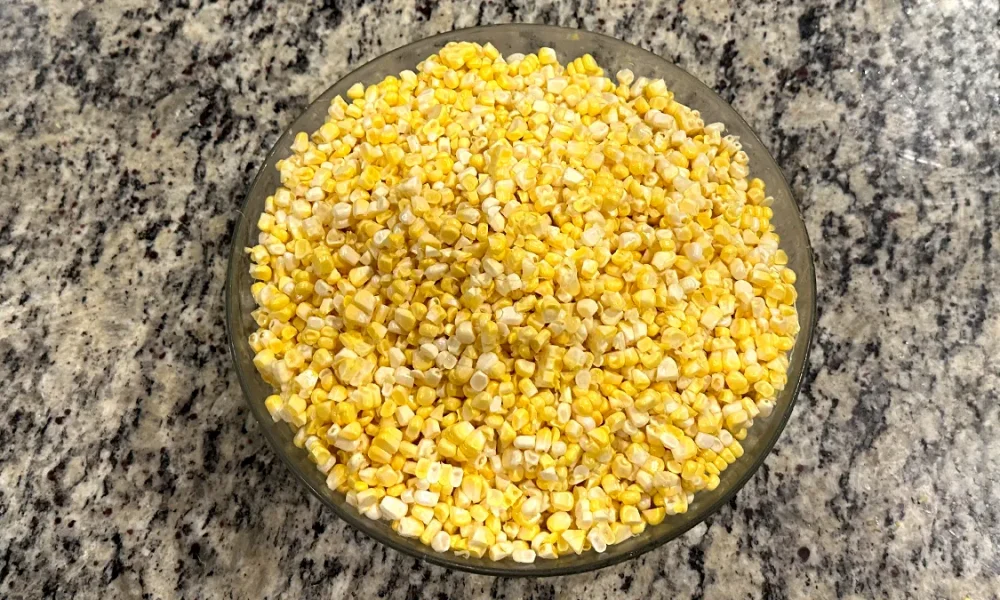 Corn kernels sitting in a glass bowl on the counter.