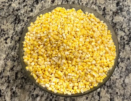 Corn kernels sitting in a glass bowl on the counter.