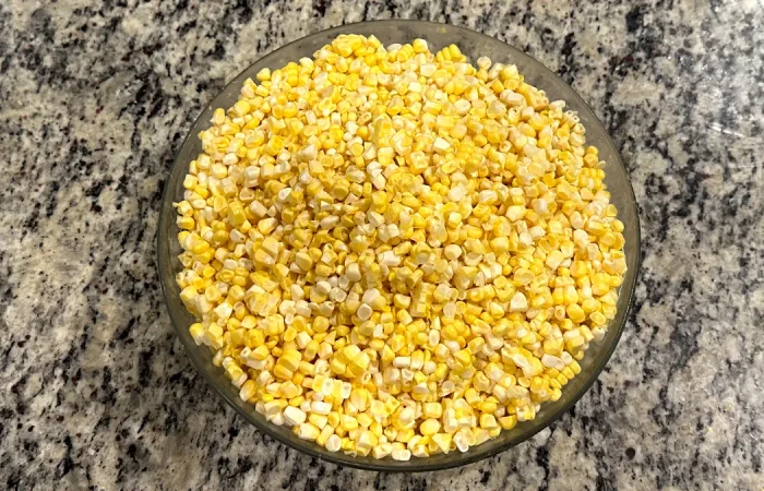 Corn kernels sitting in a glass bowl on the counter.