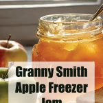 The image showcases a jar of golden Granny Smith apple freezer jam, glowing in natural light with apples placed around it. The text overlay in bold letters reads "Granny Smith Apple Freezer Jam," with the website "PreservingGuide.com" beneath it. The warm setting and focus on the jam suggest a fresh, homemade preserve ideal for canning enthusiasts looking to store apple jam in the freezer.