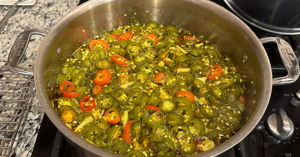 Candied jalapeno rings in a large pot sitting on the stove.