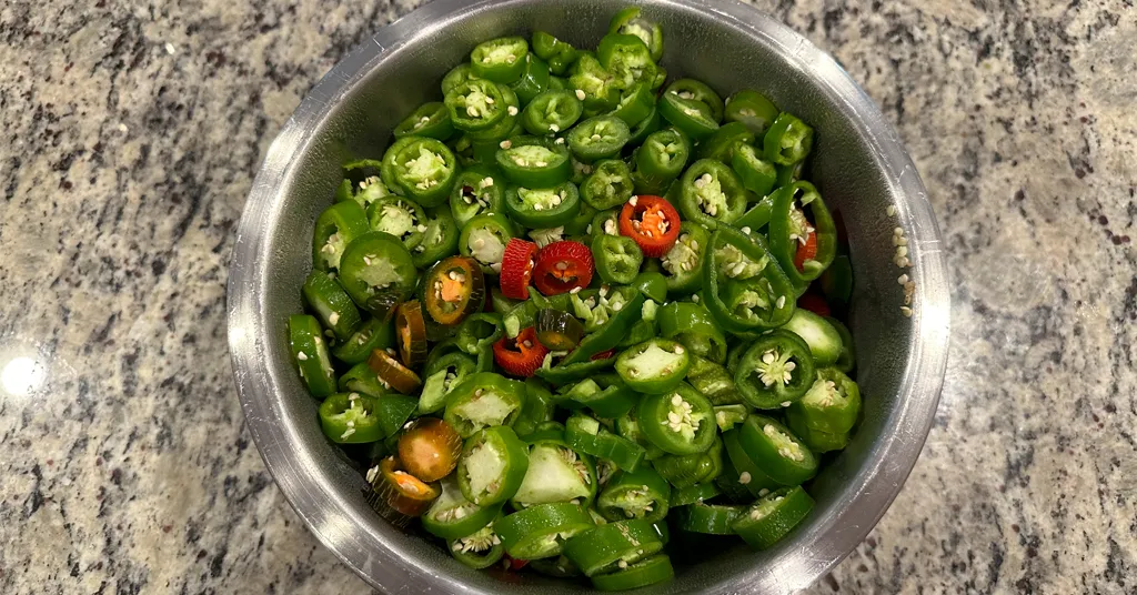 Bowl of jalapeno sliced jalapeno rings in green, orange, and red colors.