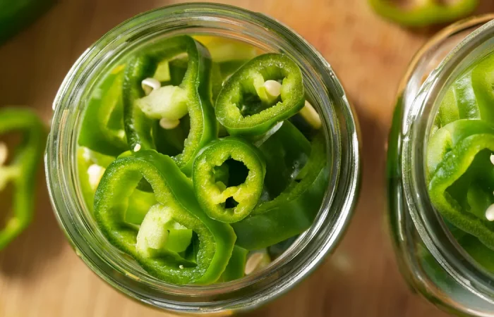 Pickled Hatch Peppers rings in a mason jar prepared to be pickled for canning.