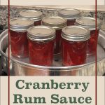 This image highlights jars of cranberry rum sauce in a canning setup, with condensation on the jars suggesting they were freshly processed. The overlay text reads "Steam Canning Cranberry Rum Sauce," framed in a minimalist design that emphasizes the preservation method. A jar icon at the bottom reinforces the canning theme.