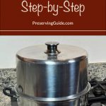 A stainless steel atmospheric steam canner with a black knob on the lid, set on a stovetop with a speckled countertop in the background. The text overlay reads 'How To Steam Can Step-by-Step' with 'PreservingGuide.com,' ideal for detailed guides on steam canning techniques and home food preservation.