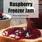 Close-up of a slice of bread topped with vibrant blueberry raspberry freezer jam, placed on a wooden surface. In the background, a jar of jam and a small bowl of fresh blueberries and raspberries add a rustic touch. The text overlay reads: 'Blueberry Raspberry Freezer Jam - PreservingGuide.com.'