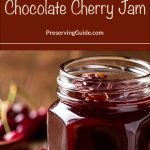 This image features an open jar of chocolate cherry jam with a glossy finish and visible cherry chunks, placed on a rustic wooden surface. The backdrop includes fresh cherries and a blurred, natural setting, creating a warm and inviting feel. Overlaid text reads: "How To Steam Can Chocolate Cherry Jam" with "PreservingGuide.com" written underneath, emphasizing the homemade preservation theme.