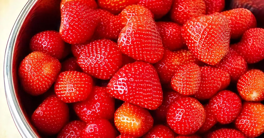 Fresh strawberries sitting in a silver bowl.