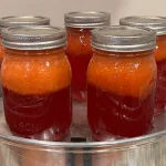 Five mason jars of Strawberry lemonade concentrate that have been processed in a steam canner.