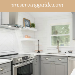 Modern kitchen with a sleek glass-topped stove and gray cabinetry, featuring text overlay that reads “Master Canning on Glass Stoves: 5 Tips” with the website name preservingguide.com. Ideal for a guide or blog post about safely canning on glass cooktops.