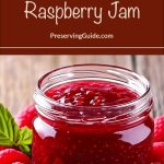 A clear glass jar filled with homemade raspberry jam sits on a rustic wood surface, surrounded by fresh raspberries and green leaves. Text above reads “How To Can Raspberry Jam” with the website PreservingGuide.com listed underneath.