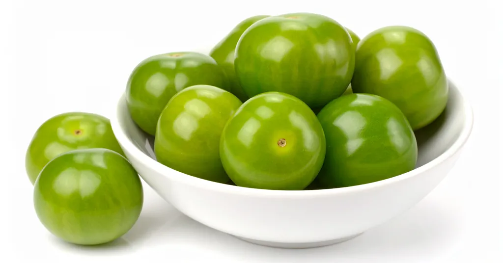 Green Tomatillos in a white bow sitting on a white surface.